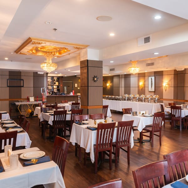 The King of Tandoor & Biryani House dining room with set tables and a buffet line.