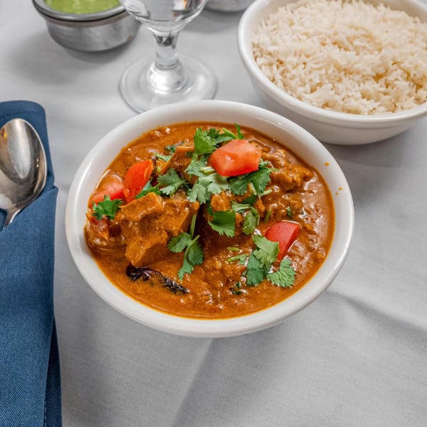 Indian chicken curry with tomatoes and cilantro, served with rice and green chutney.