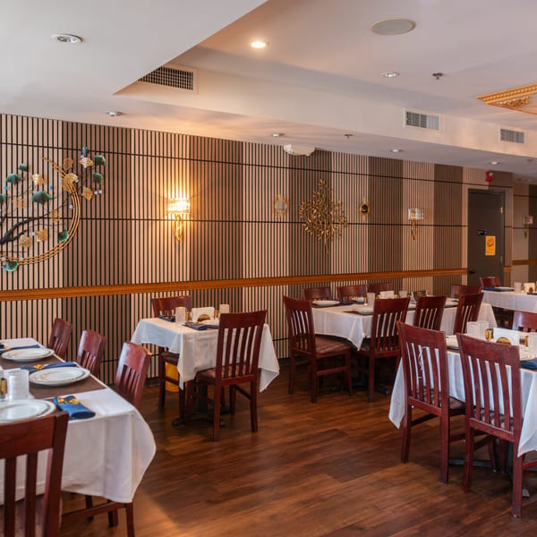 Interior of King of Tandoor & Biryani House, showing dining tables with white tablecloths and wooden chairs.