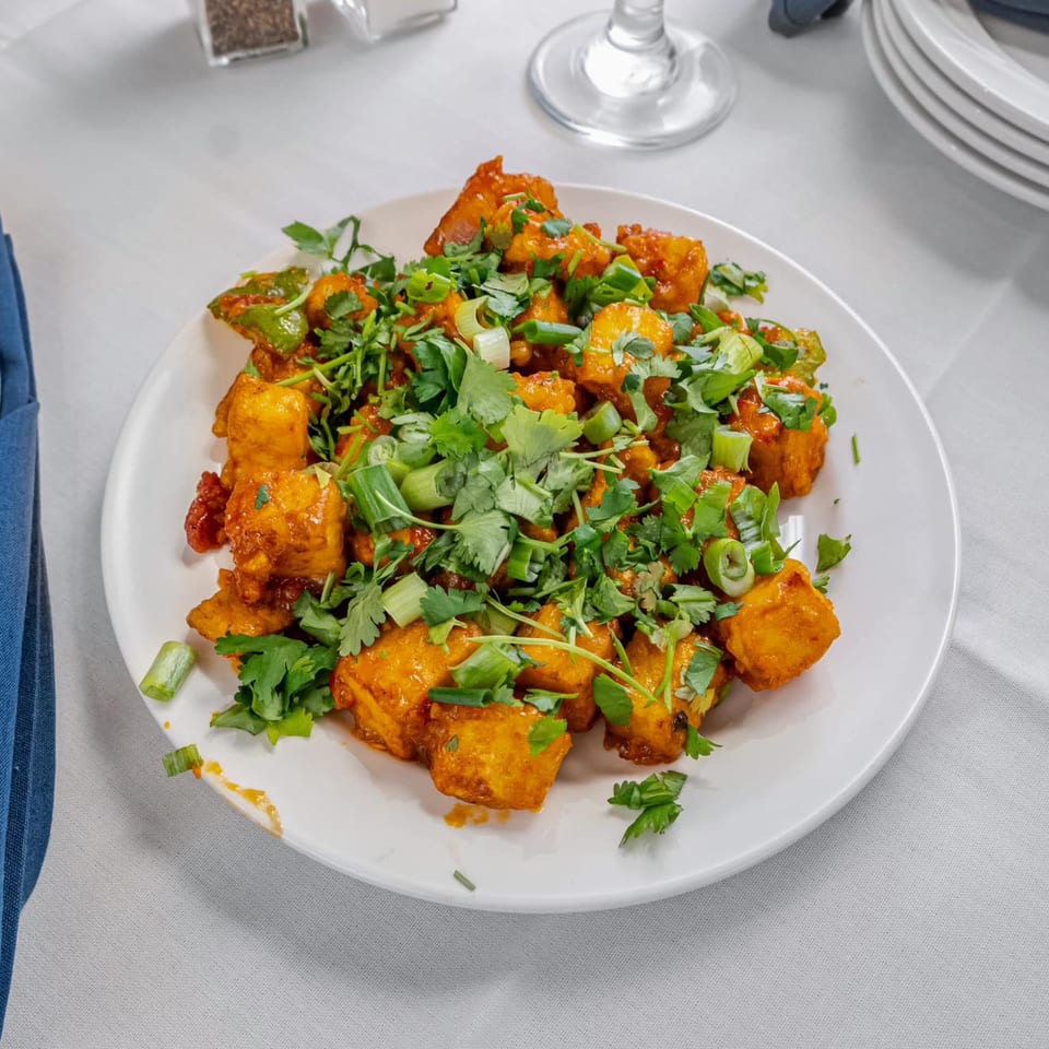 Indian chili paneer, golden fried and tossed in a spicy sauce, garnished with fresh cilantro and scallions.